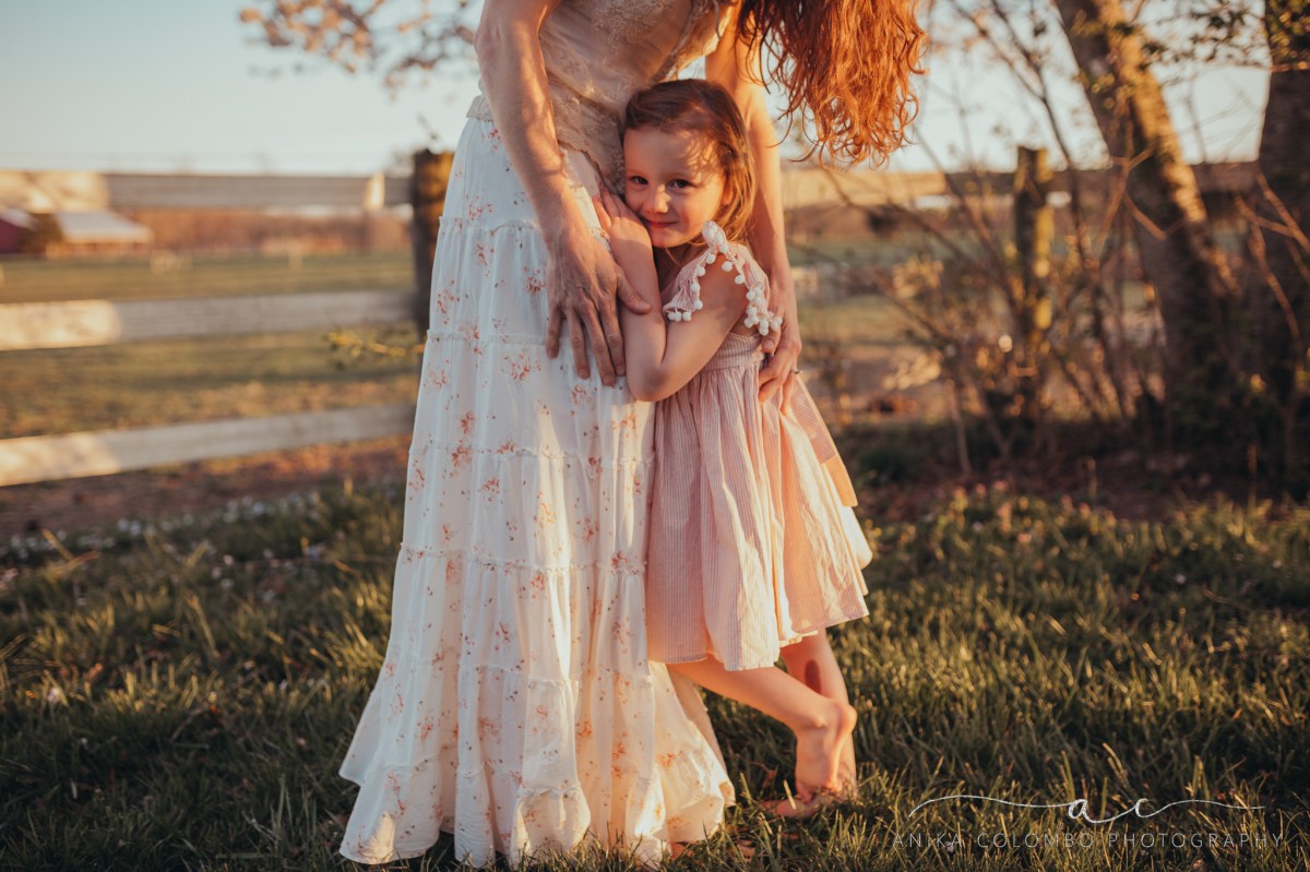 mother hugging daughter as she looks into the camera
