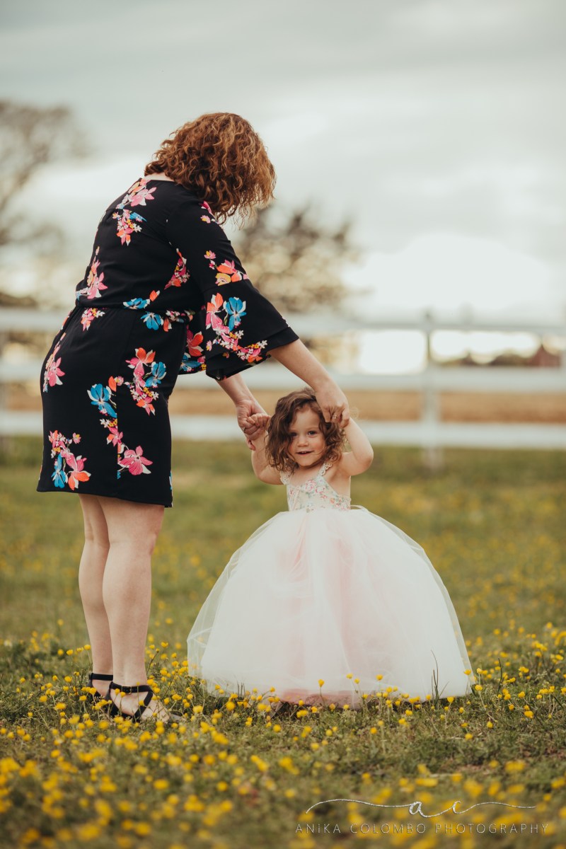 mother twirling daughter in a tutu in a field of buttercups