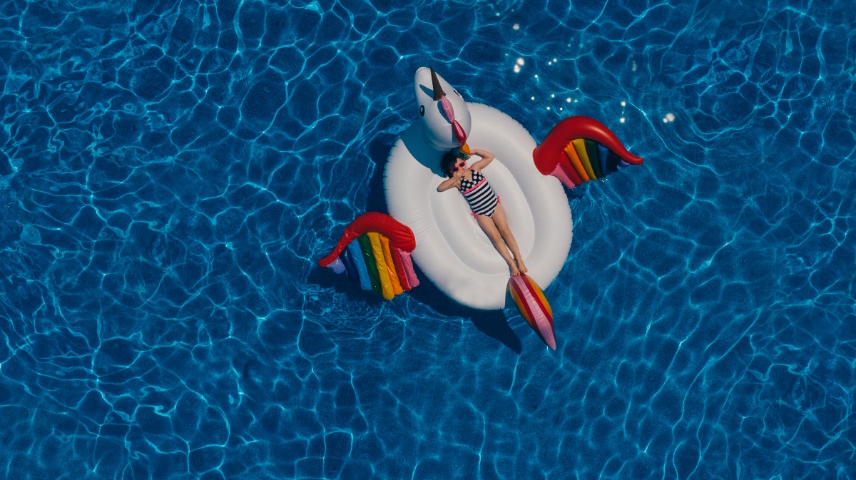 aerial view of child on a unicorn float in a pool