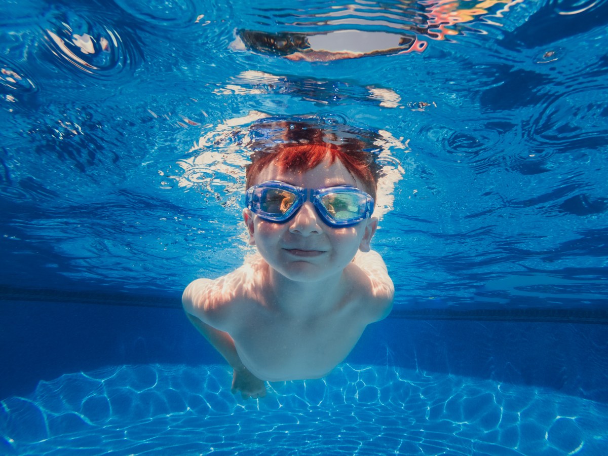 child swimming in the pool with goggles