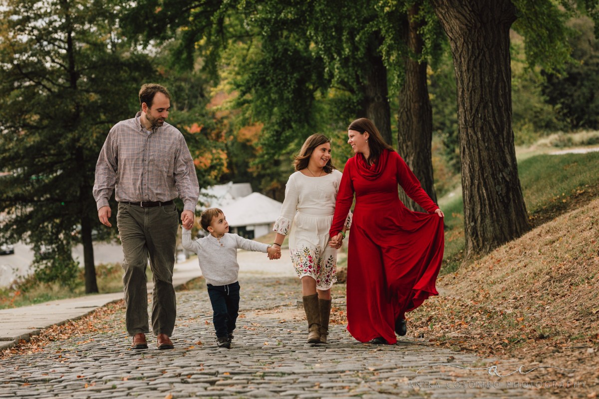 family walking on cobblestone street in richmond va holding hands and laughing