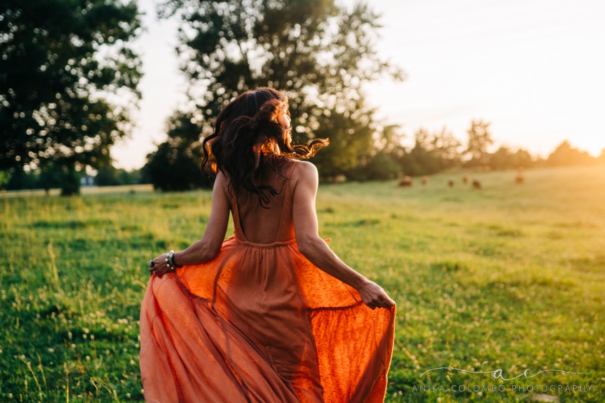 woman running through a field at sunset