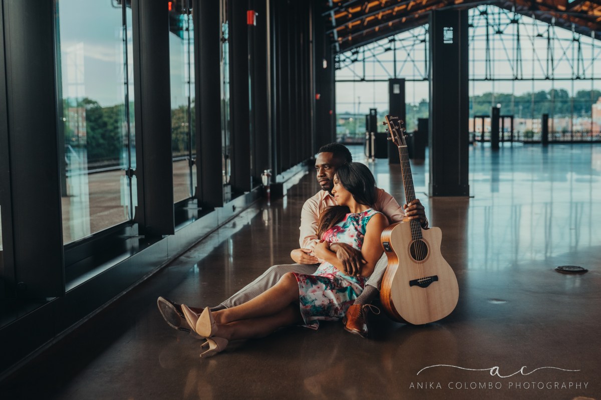 couple sitting on the floor of mainstreet train station in richmond va embracing and holding a guitar